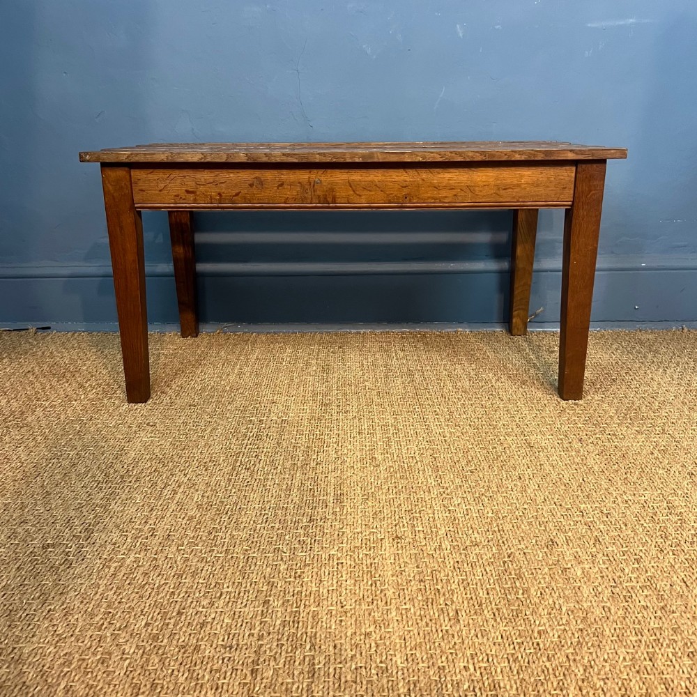 A low Edwardian solid oak luggage rack featuring a slatted top surface and sturdy square legs.