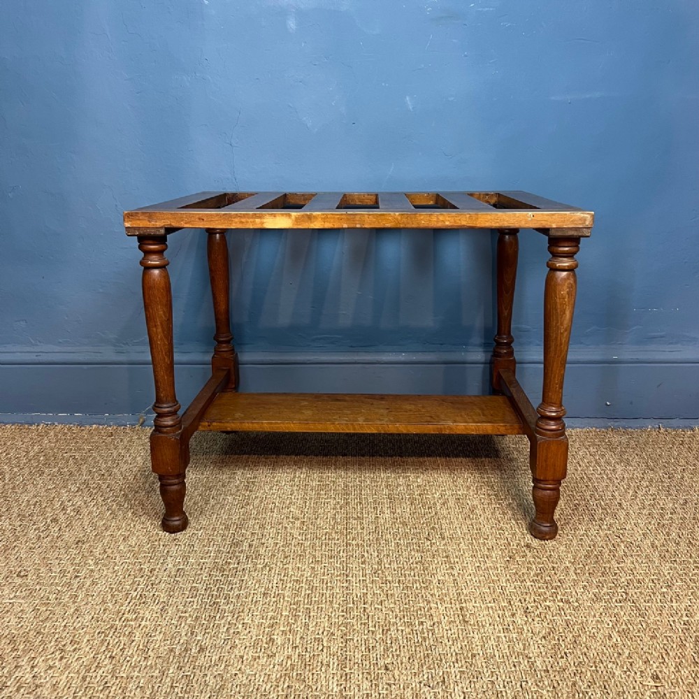 A late 19th-century Aesthetic Movement rectangular beech luggage rack featuring a slatted top surface, turned legs, and a solid lower stretcher shelf.