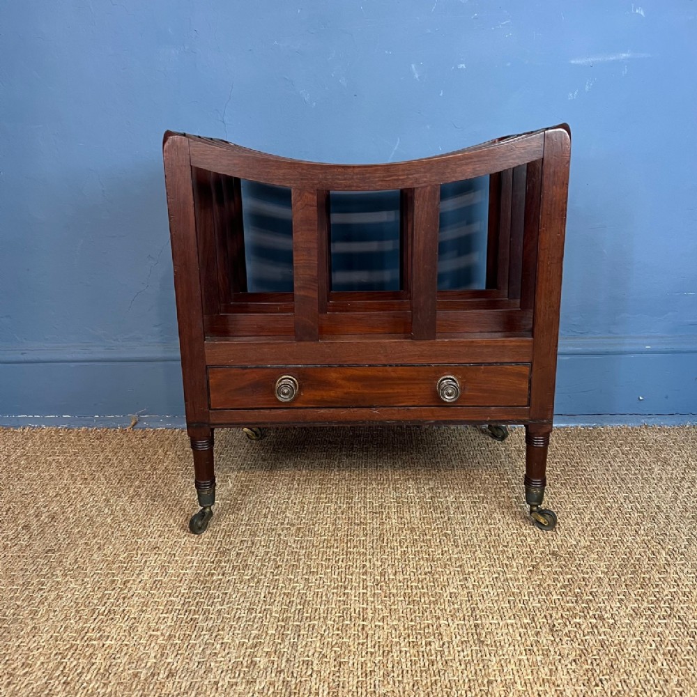 A Georgian mahogany Canterbury with slatted curved dividers, a single lower drawer, and turned legs set on brass castors.
