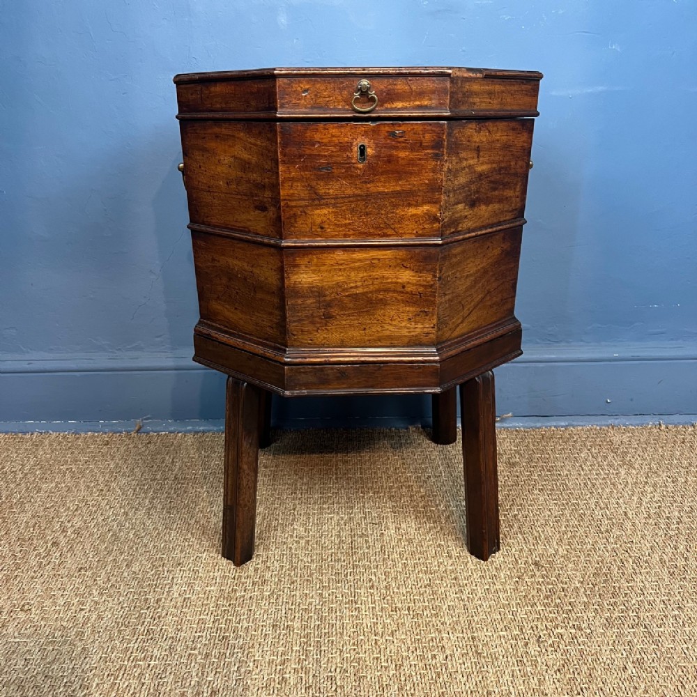 A George III hexagonal mahogany wine cooler featuring a hinged lid, brass side carrying handles, and straight legs.