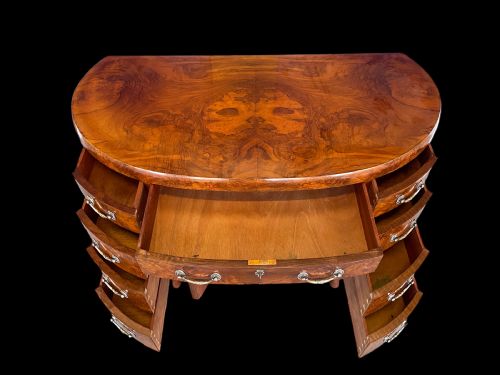 fig 1. A curved Art Deco burr walnut pedestal desk featuring a figure-matched grain top, central drawer, and multiple side drawers with metal handles.
