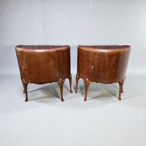 fig 2. A pair of semi-circular Art Deco side cabinets featuring warm brown figured wood veneers, single curved cupboard doors, metal handles, and slender cabriole legs.