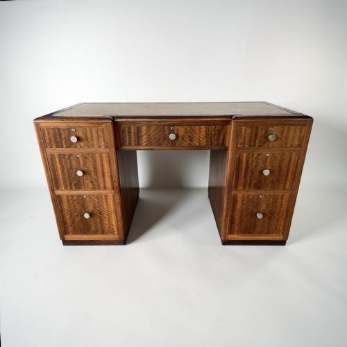 fig 1. An Art Deco twin-pedestal executive desk featuring figured wood grain veneer, round metal knobs, and a central kneehole with drawers.