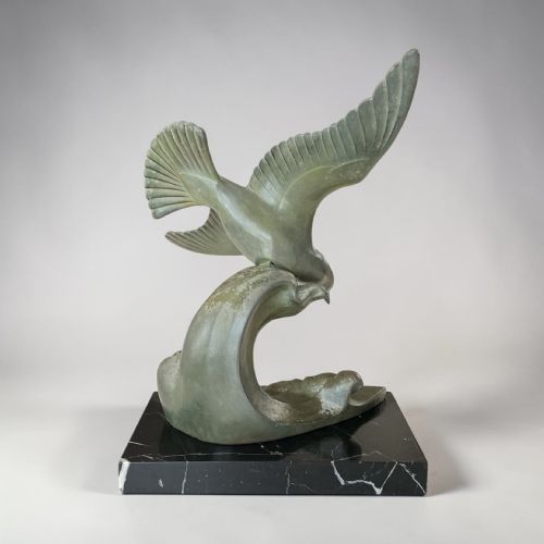 fig 1. An Art Deco verdigris green patinated metal sculpture depicting a seagull swooping over stylised ocean waves, mounted on a dark marble base.