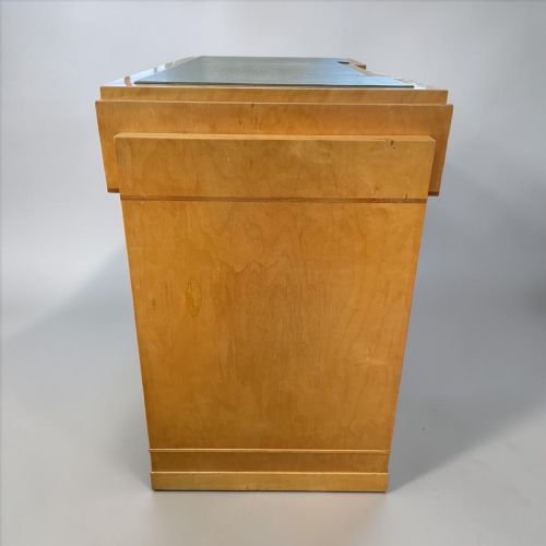 fig 1. An Art Deco light wood writing desk featuring an inset leather writing surface, three drawers with rectangular wooden pulls, and a central keyhole.