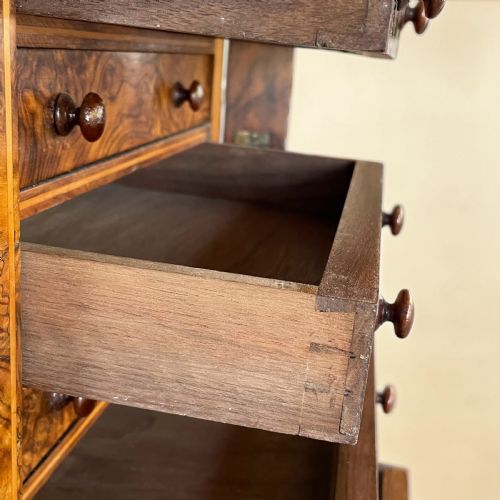 fig 1. A tall Victorian burr walnut Wellington chest featuring ten drawers with turned wooden knobs and a side-locking hinged flap.