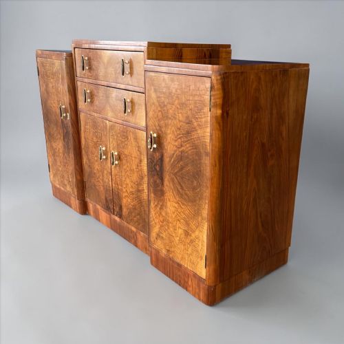 fig 1. An Art Deco sideboard made of figured walnut veneer with rounded corners, double central drawers, twin side cupboards, and decorative drop handles.