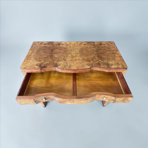 fig 1. An Art Deco burr walnut serving table featuring a shaped serpentine front, drawers with metal pulls, and an open lower shelf.