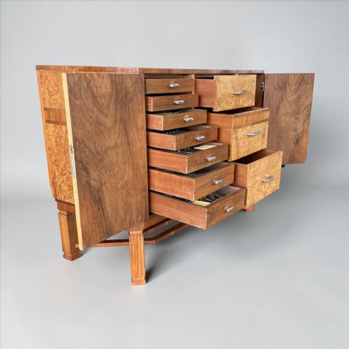 fig 1. An Art Deco burr wood sideboard featuring central drawers, side cupboards, band inlay, chrome handles, and a geometric stretcher base.