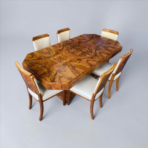 fig 1. An Art Deco burr walnut dining table featuring a richly figured canted top paired with six matching chairs upholstered in cream leather.