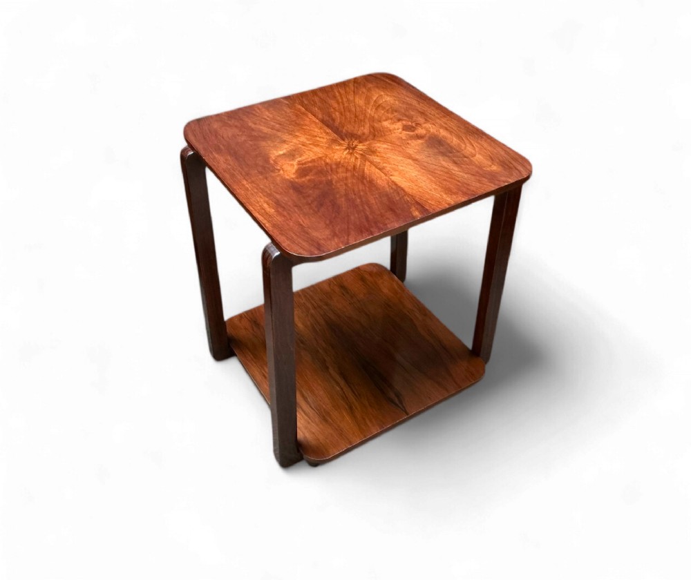 An antique Art Deco wooden tea trolley featuring a square top with burr walnut veneer and an open lower shelf supported by curved uprights.