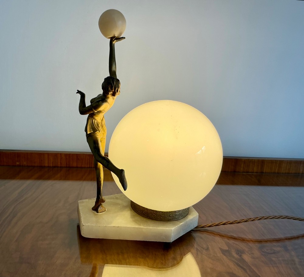 An Art Deco table lamp featuring a bronze figurine of a dancing lady posed beside a spherical frosted glass shade set on a marble base. View II