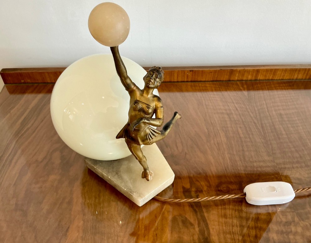 An Art Deco table lamp featuring a bronze figurine of a dancing lady posed beside a spherical frosted glass shade set on a marble base. View III