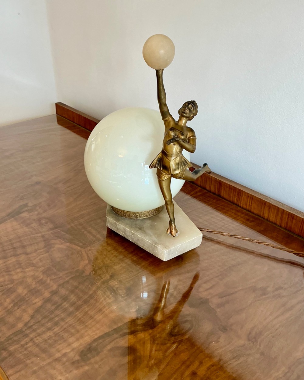 An Art Deco table lamp featuring a bronze figurine of a dancing lady posed beside a spherical frosted glass shade set on a marble base. View IV