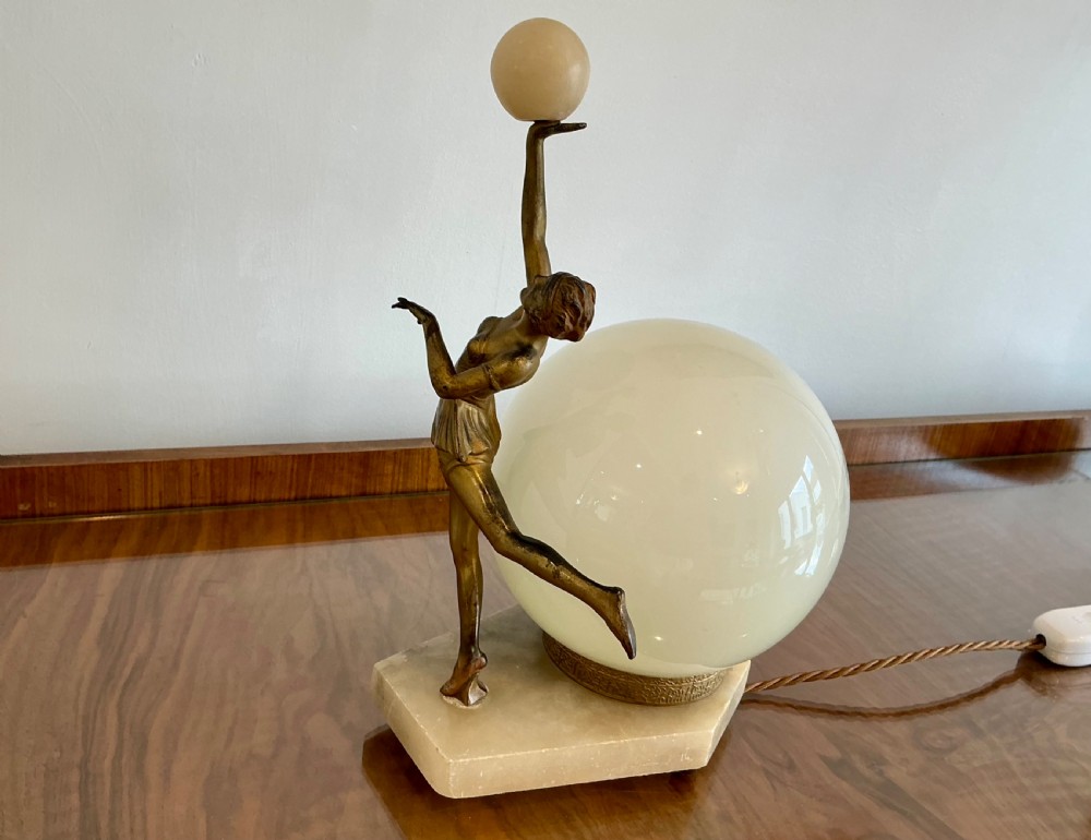 An Art Deco table lamp featuring a bronze figurine of a dancing lady posed beside a spherical frosted glass shade set on a marble base. View VII