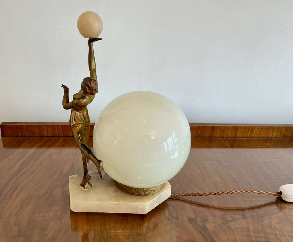An Art Deco table lamp featuring a bronze figurine of a dancing lady posed beside a spherical frosted glass shade set on a marble base. View VIII