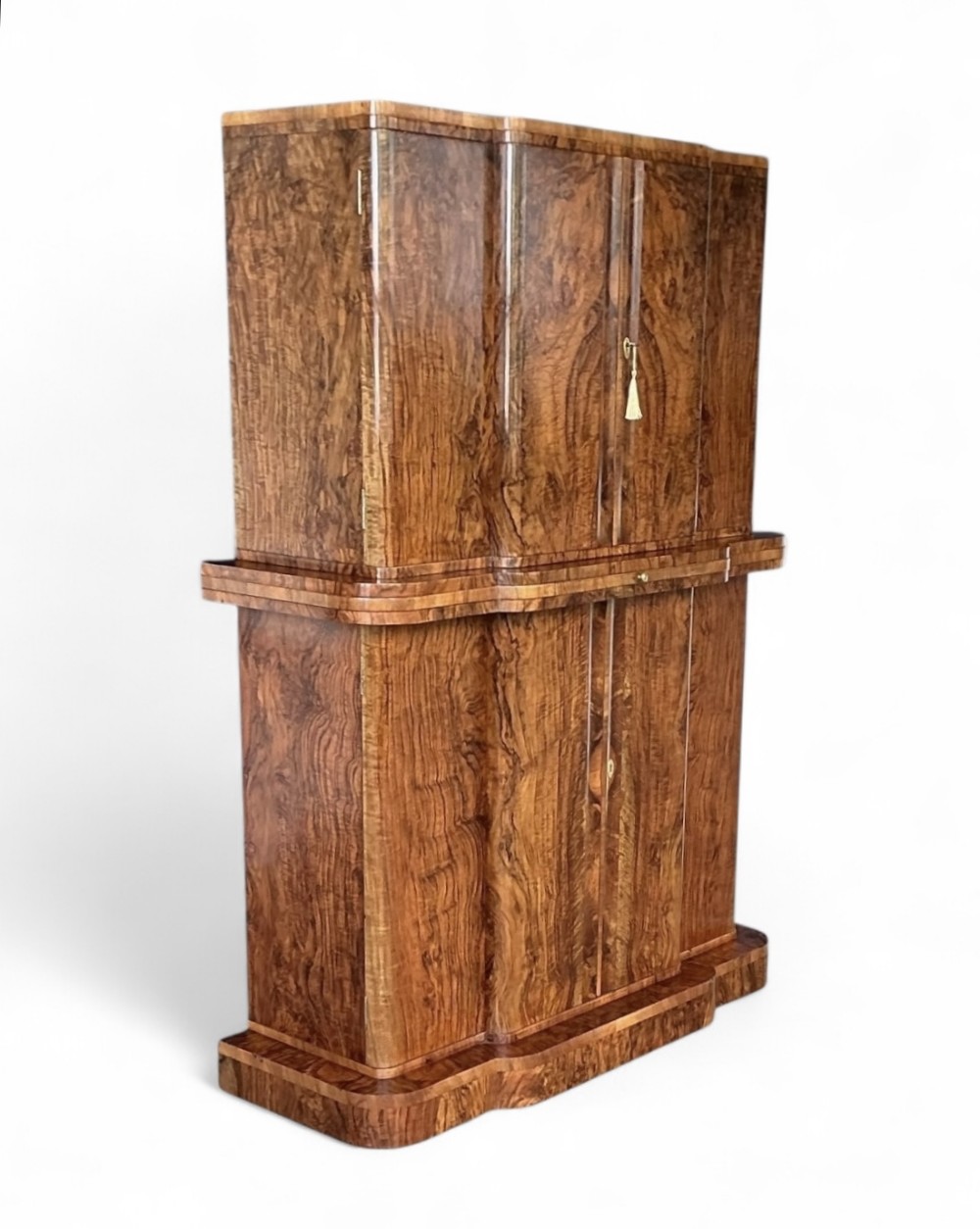 A two-tiered Art Deco burr walnut cocktail cabinet featuring curved outer edges and two double-door compartments with a key tassel.