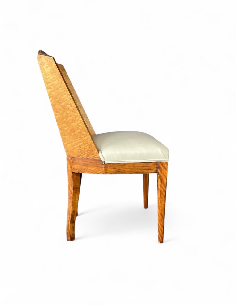 An Art Deco side chair featuring a geometric blonde wood veneer backrest and a light cream leather upholstered seat.
