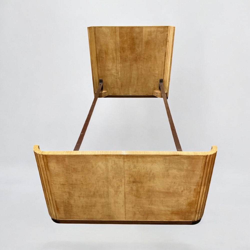 An Art Deco single bed frame featuring a blonde wood headboard and footboard with fluted edges and metal side rails.