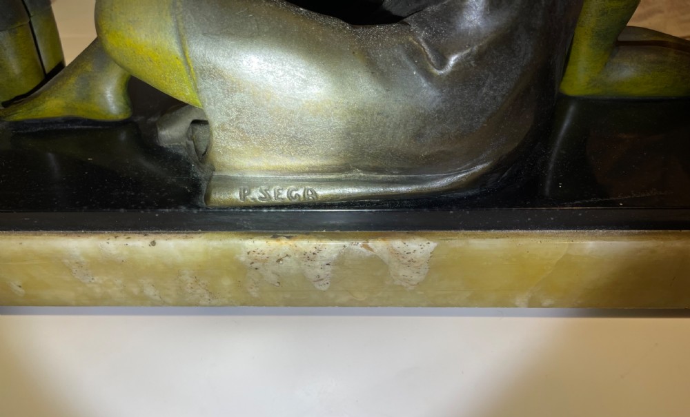 An Art Deco patinated metal sculpture depicting a seated woman flanked by two children, set on a layered black marble and cream onyx base. View VII