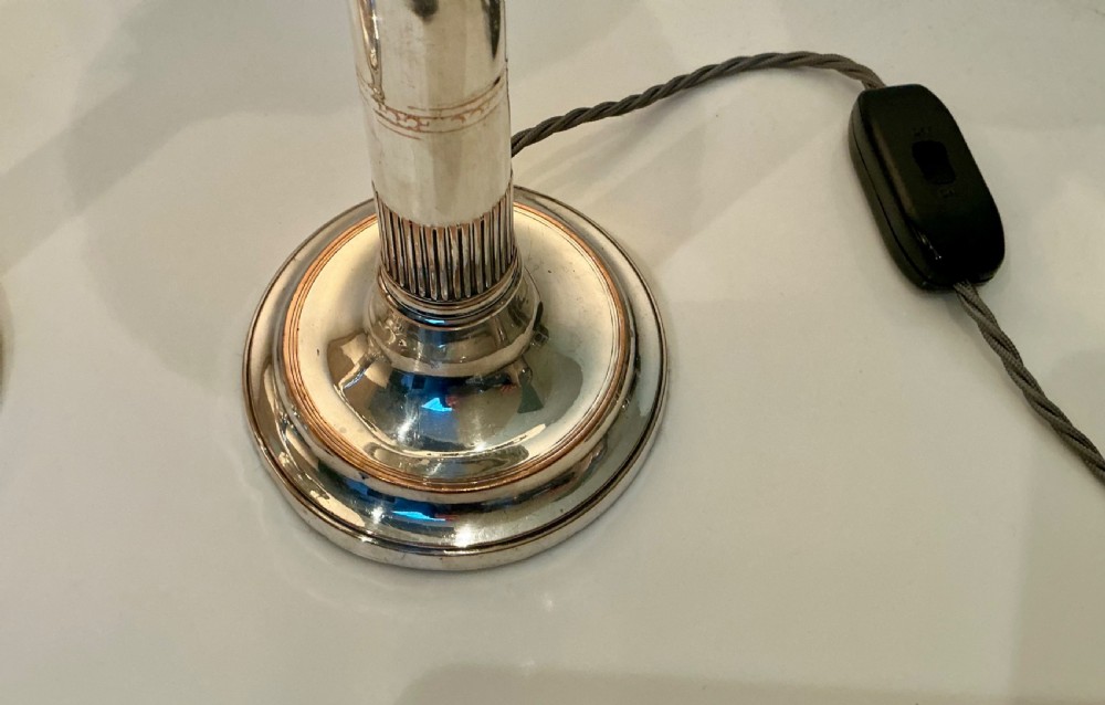 A pair of silver-toned Art Deco table lamps featuring fluted column stems and spherical frosted glass shades with moulded circular motifs. View VI