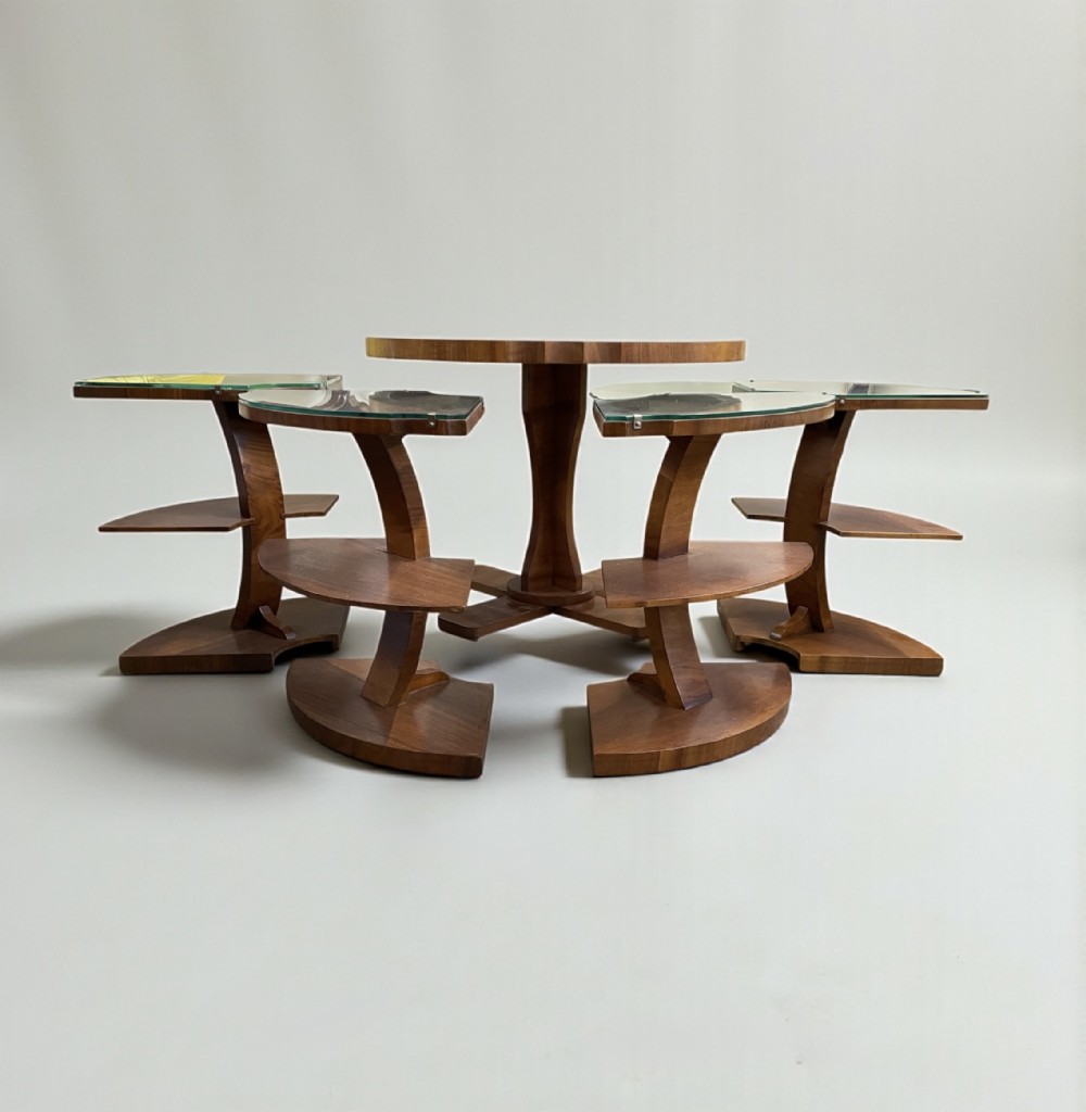 An Art Deco walnut nest of tables featuring a central round coffee table surrounded by four matching curved quadrant side tables with glass tops.