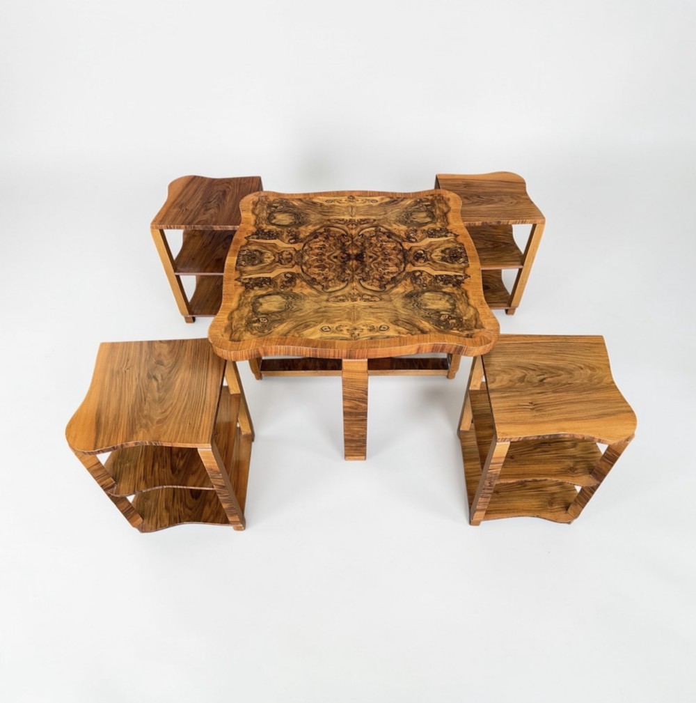 An Art Deco burr walnut nest of five tables featuring a main central square table surrounded by four fitted curved side tables.