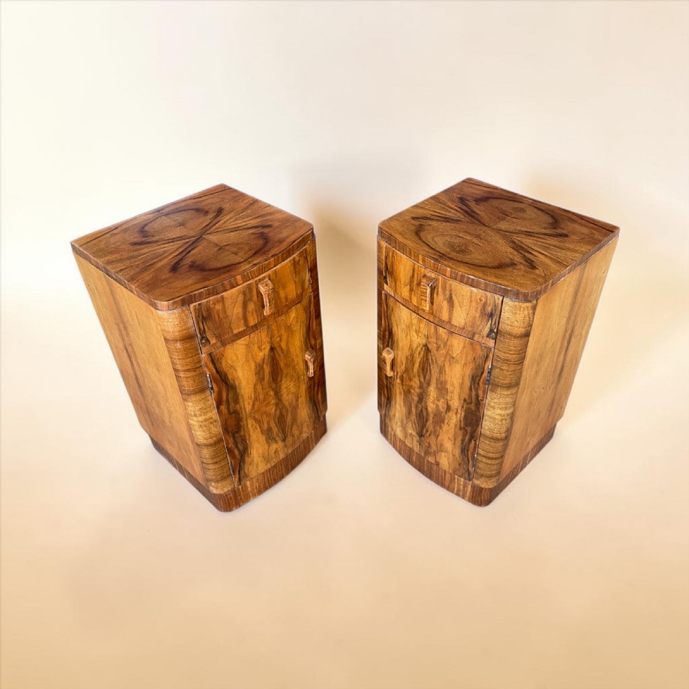 A matching pair of Art Deco walnut bedside cabinets featuring book-matched wood grain, single top drawers, rounded sides, and lower cupboard doors. View II