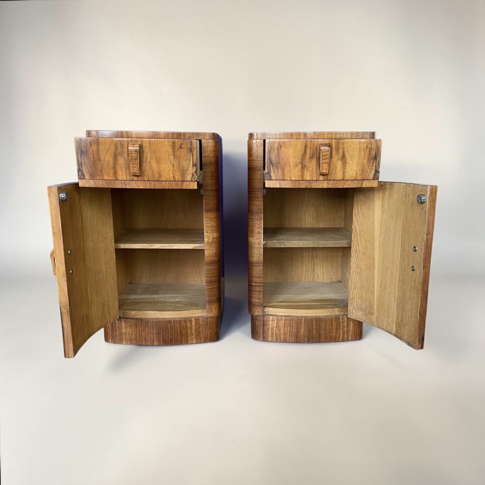 A matching pair of Art Deco walnut bedside cabinets featuring book-matched wood grain, single top drawers, rounded sides, and lower cupboard doors. View IV