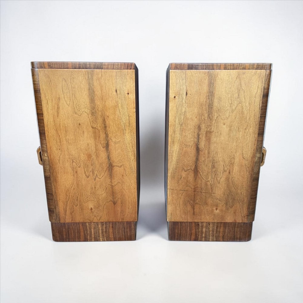 A matching pair of Art Deco walnut bedside cabinets featuring book-matched wood grain, single top drawers, rounded sides, and lower cupboard doors. View VII