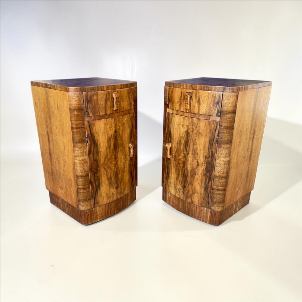 A matching pair of Art Deco walnut bedside cabinets featuring book-matched wood grain, single top drawers, rounded sides, and lower cupboard doors. View IX