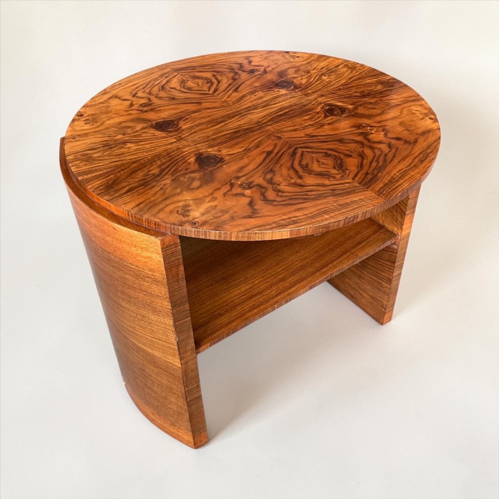 A circular Art Deco coffee table made of figured walnut veneer with a quartered top pattern, curved side supports, and an lower shelf. View IV