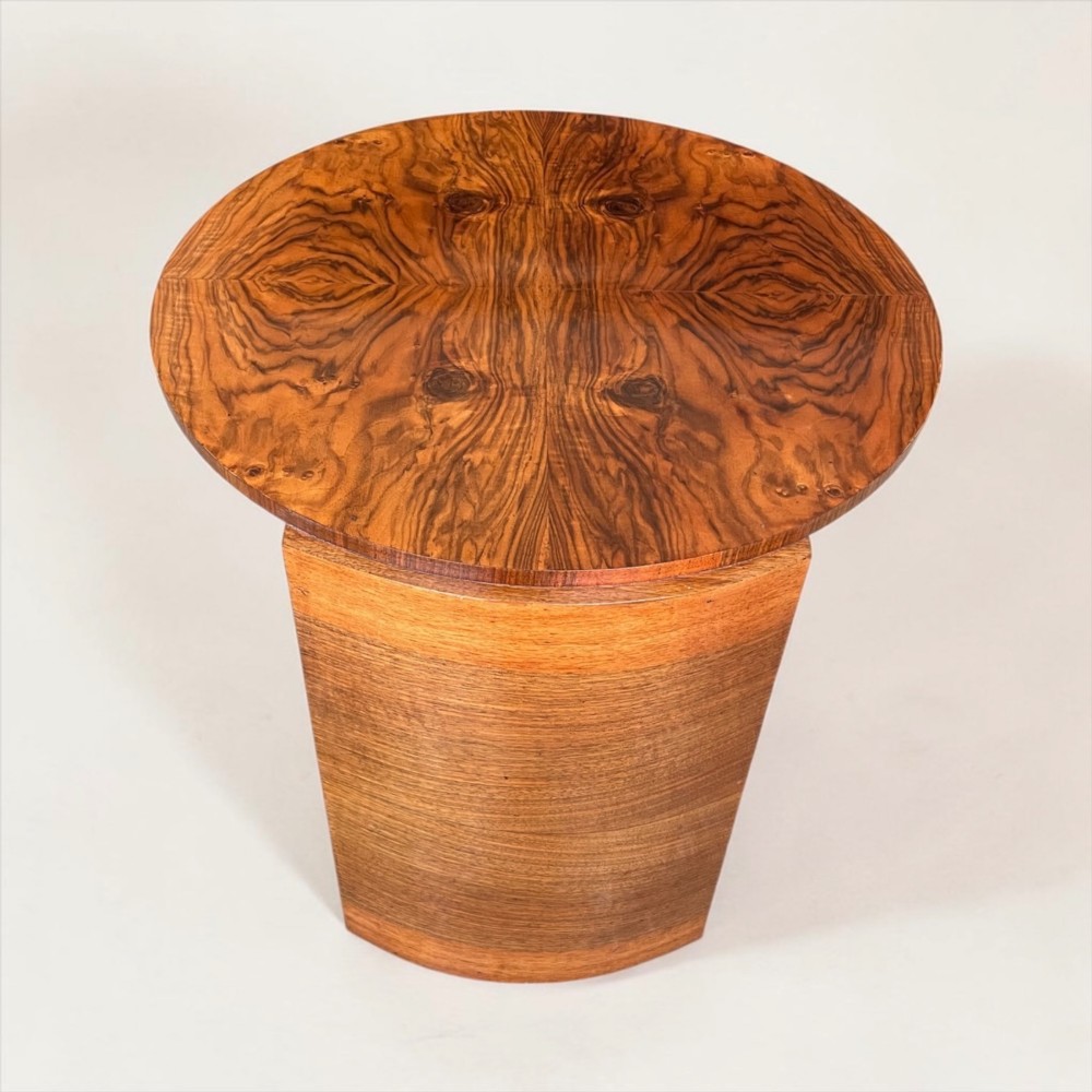A circular Art Deco coffee table made of figured walnut veneer with a quartered top pattern, curved side supports, and an lower shelf. View VIII