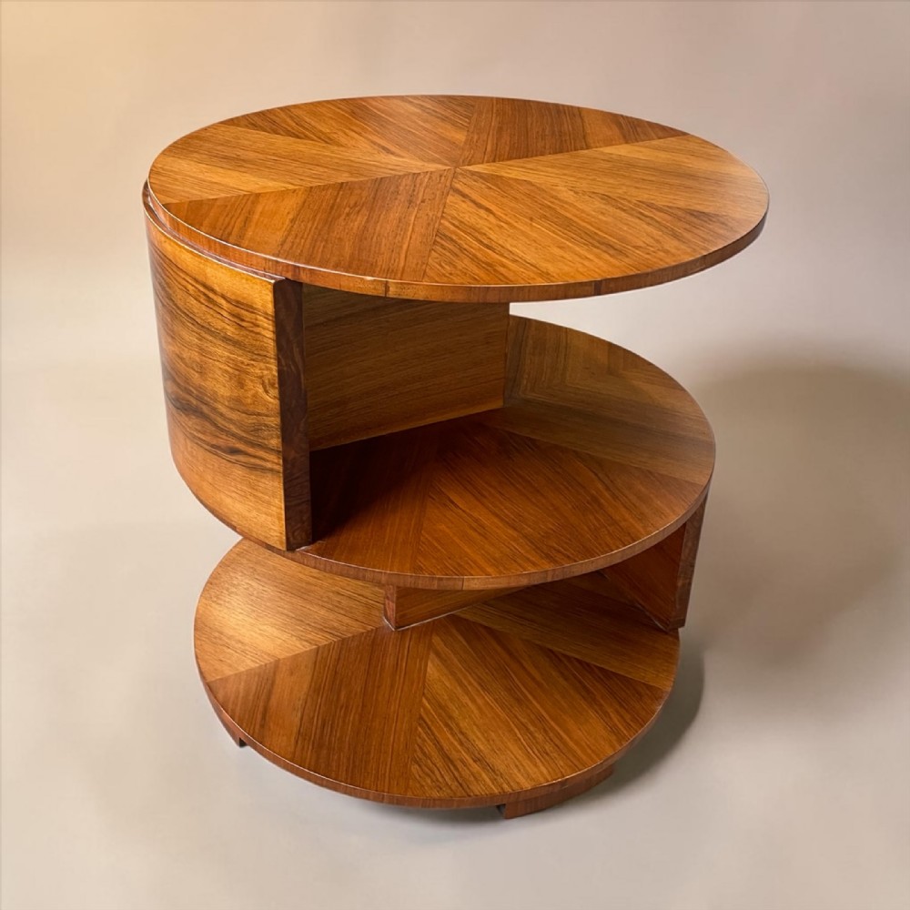A circular Art Deco walnut side table featuring three geometric tiered levels with sunburst veneer patterns.