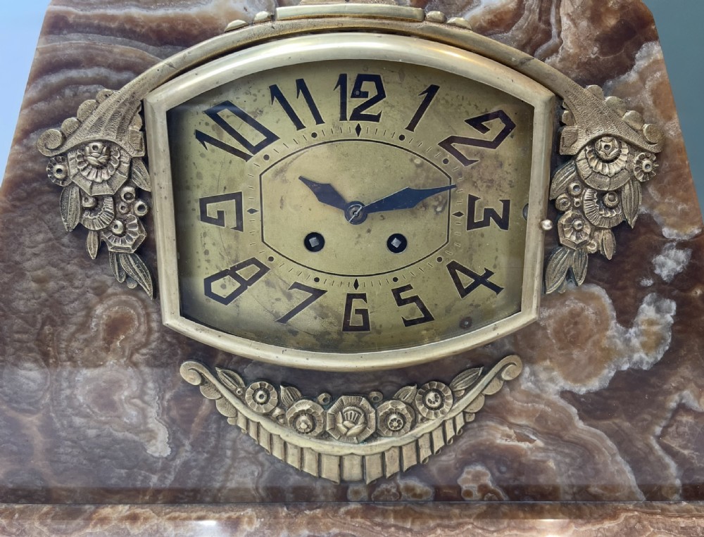 An Art Deco French mantel clock crafted from stepped brown and green onyx with silvered figural sculptures, accompanied by two matching side garnitures. View IX