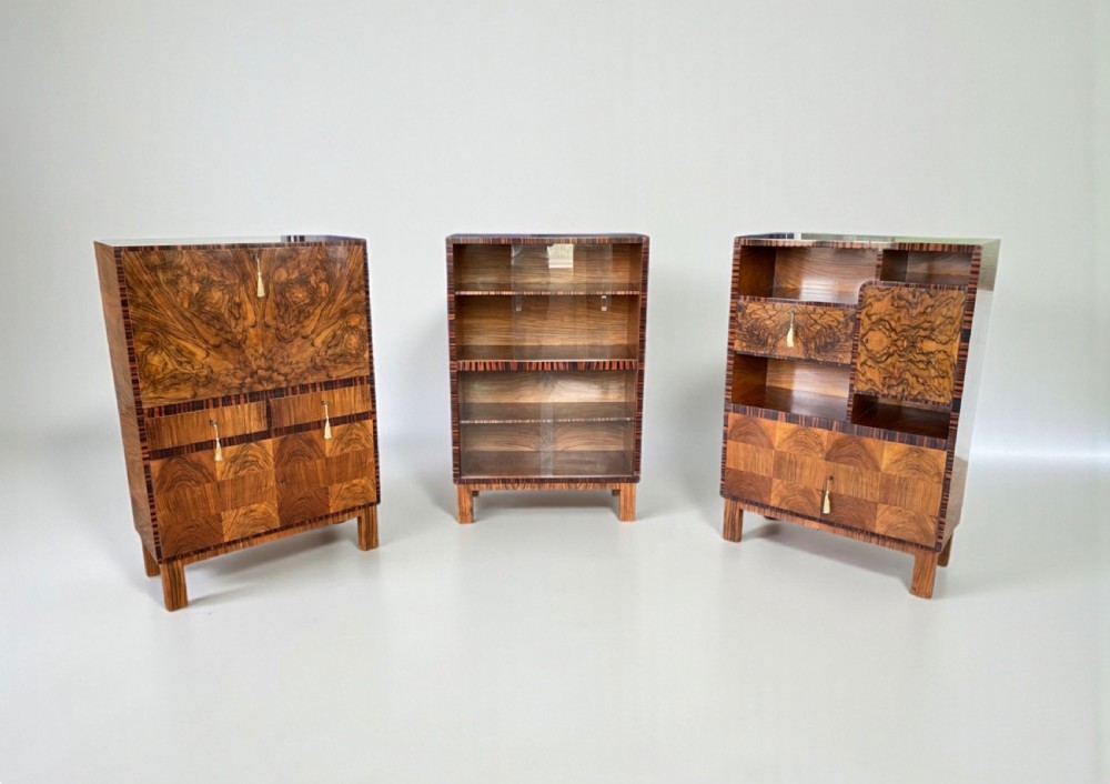 An Art Deco walnut bureau featuring a fall-front desk section revealing a fitted interior, standing on square legs with contrasting wood veneers. View X