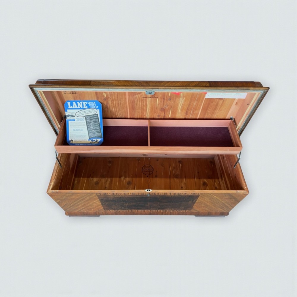 An Art Deco timber blanket chest featuring geometric chevron wood veneers and rounded waterfall edges on a stepped plinth base. View V