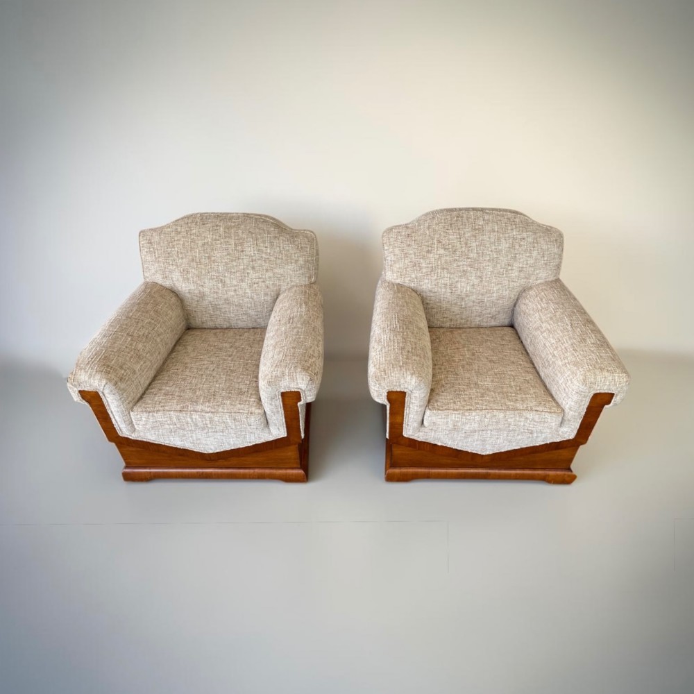 A pair of Art Deco lounge chairs featuring light beige textured upholstery and angular walnut bases. View V
