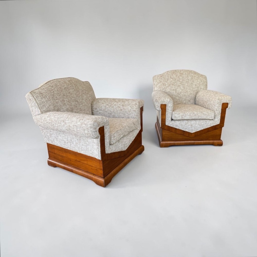 A pair of Art Deco lounge chairs featuring light beige textured upholstery and angular walnut bases. View VI
