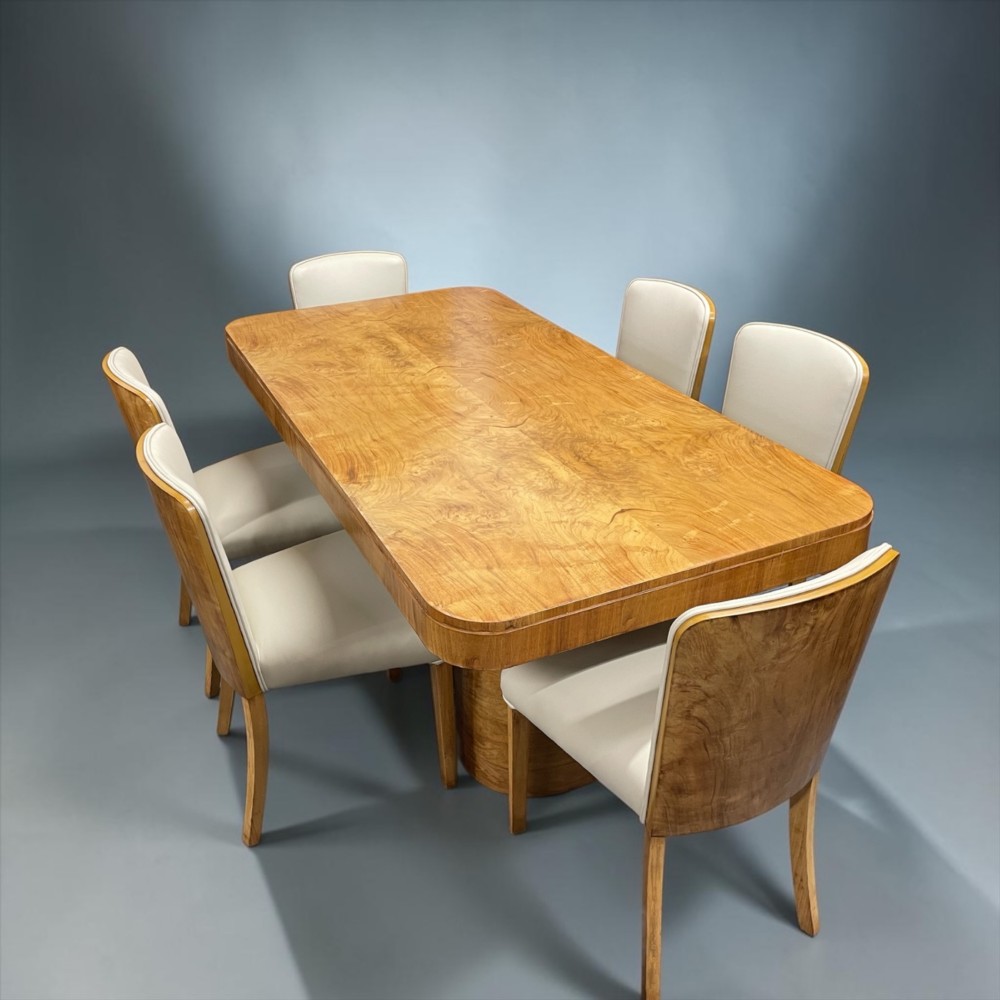 An Art Deco burr walnut dining table featuring rounded corners and a central pedestal base, accompanied by six matching cloud-back chairs upholstered in off-white leather. View II