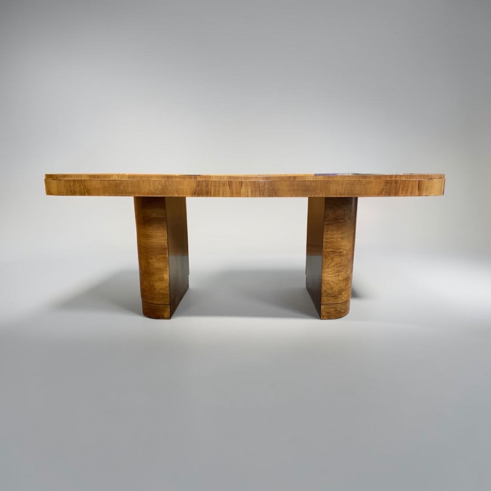 An Art Deco burr walnut dining table featuring rounded corners and a central pedestal base, accompanied by six matching cloud-back chairs upholstered in off-white leather. View XI