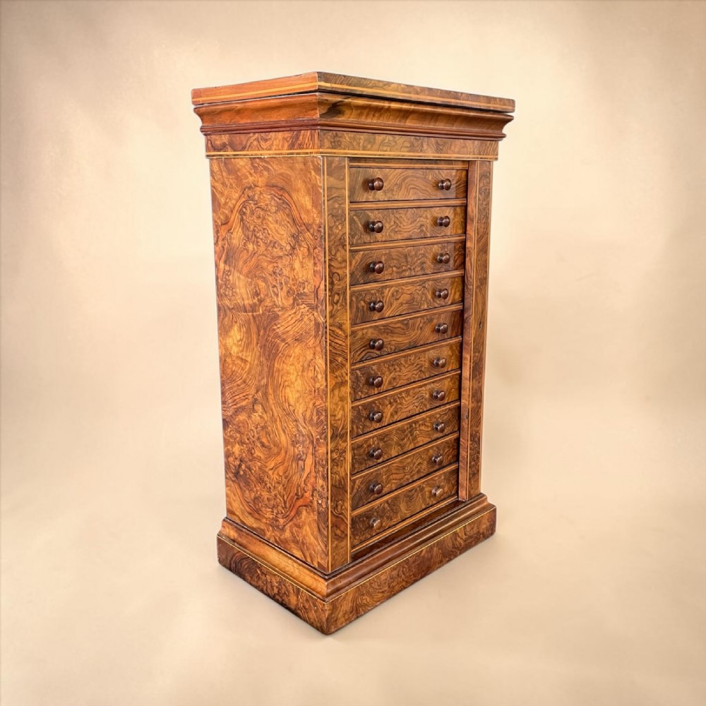 A tall Victorian burr walnut Wellington chest featuring ten drawers with turned wooden knobs and a side-locking hinged flap.