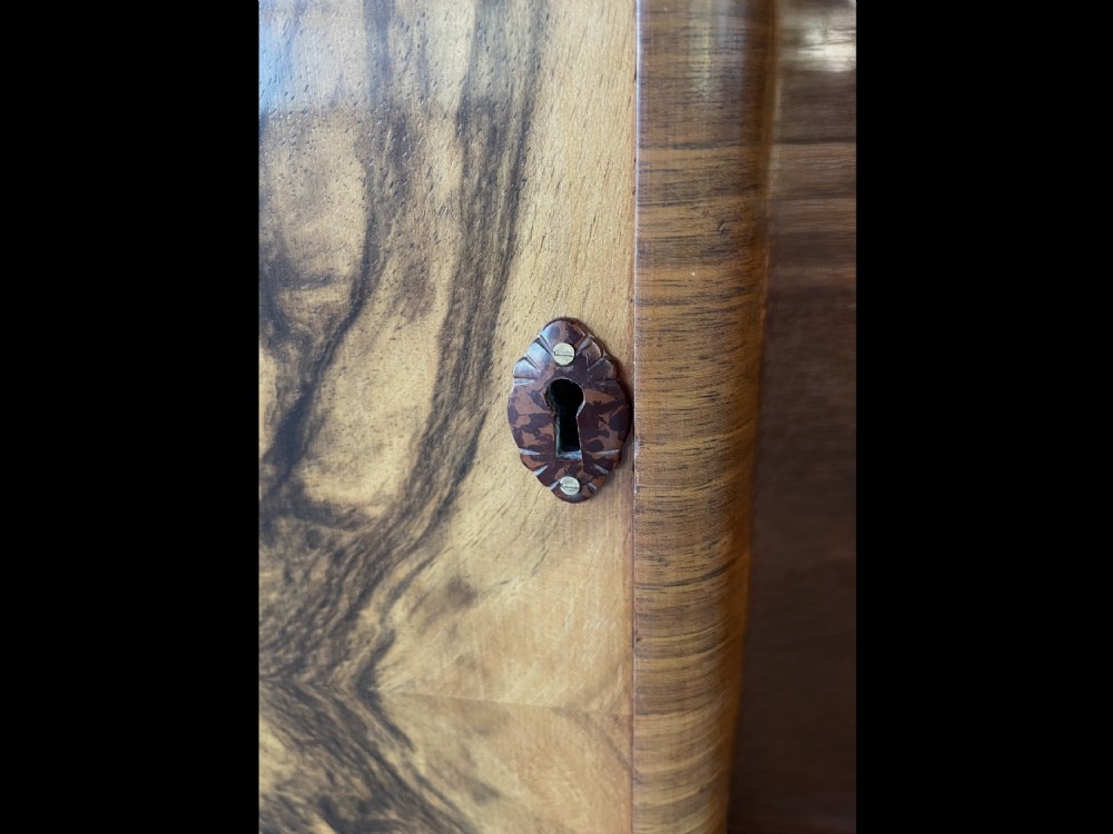 An Art Deco walnut display cabinet featuring a central arched glazed door flanked by two side doors with symmetrical book-matched wood grain pattern. View VII