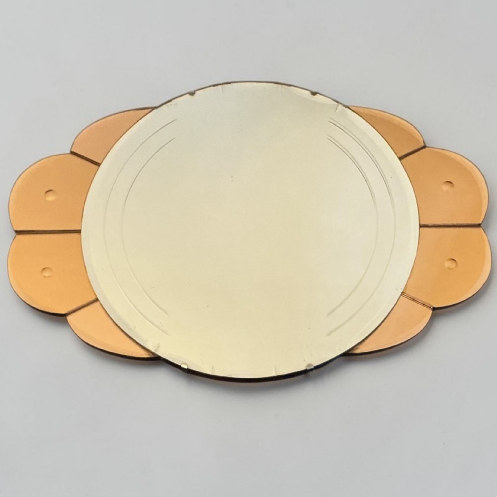 An Art Deco frameless wall mirror featuring a central silvered oval mirror with etched lines, surrounded by peach-tinted scalloped glass border panels.