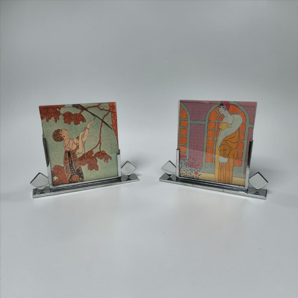 A pair of Art Deco chrome picture frames featuring stepped geometric bases with diamond accents holding glass panes.