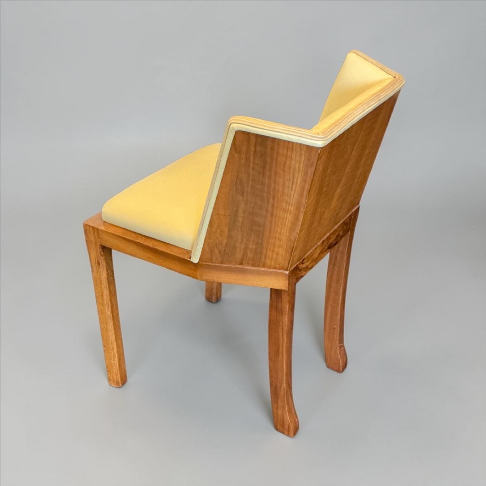An Art Deco walnut side chair featuring an angular veneered back panel and yellow leather upholstered seat with light piping.