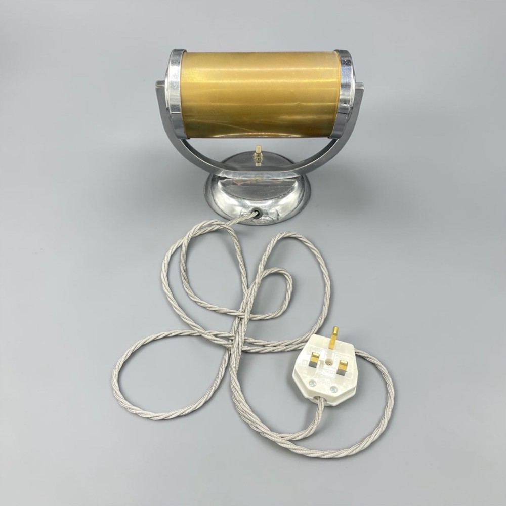 An Art Deco chrome desk lamp featuring a cylindrical beige glass shade supported by a curved metal arm on a round chrome base. View III