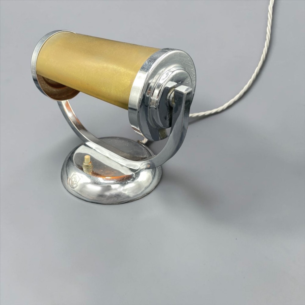 An Art Deco chrome desk lamp featuring a cylindrical beige glass shade supported by a curved metal arm on a round chrome base. View V