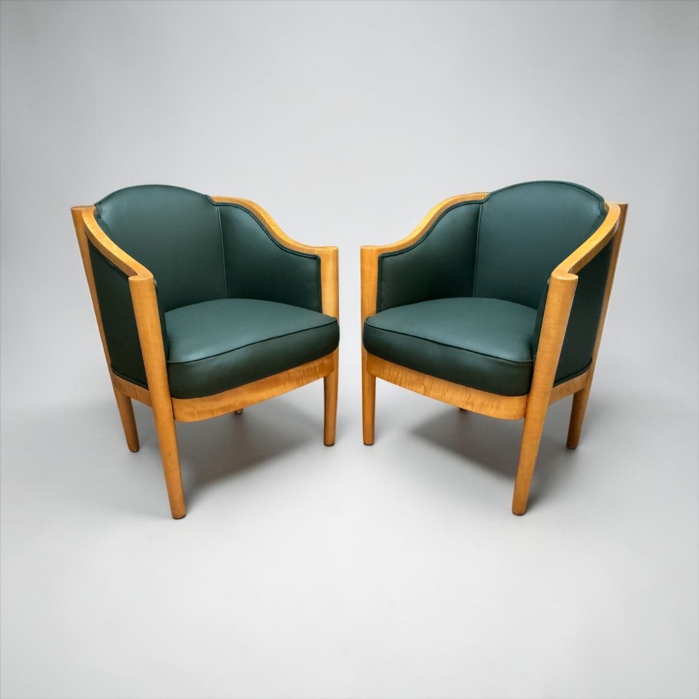 A pair of British Art Deco occasional chairs with curved light honey-toned timber frames and dark green leather upholstered seats and backrests. View II