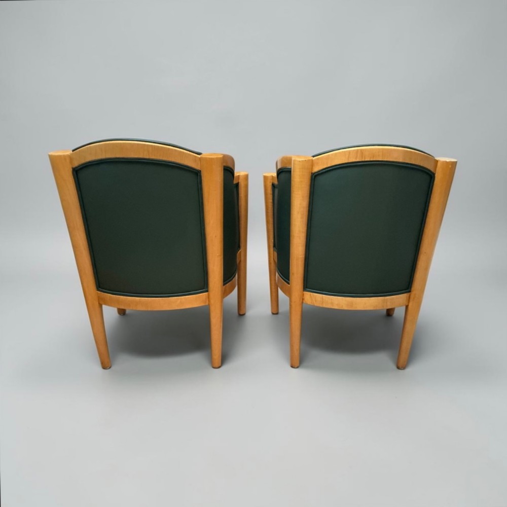 A pair of British Art Deco occasional chairs with curved light honey-toned timber frames and dark green leather upholstered seats and backrests. View V